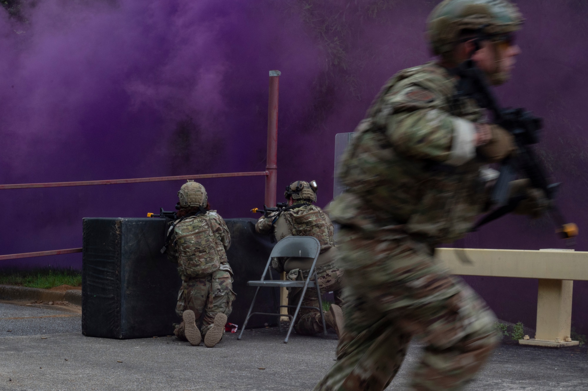 Airman take a defensive kneeling posture during a simulated attack while on mans runs off of right screen.