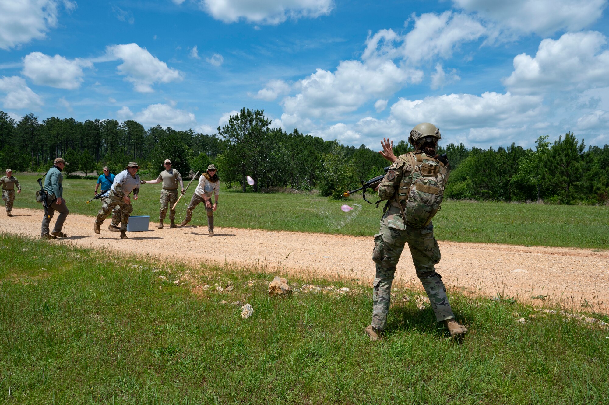 People on the left throw water balloons at an Airman on the right.