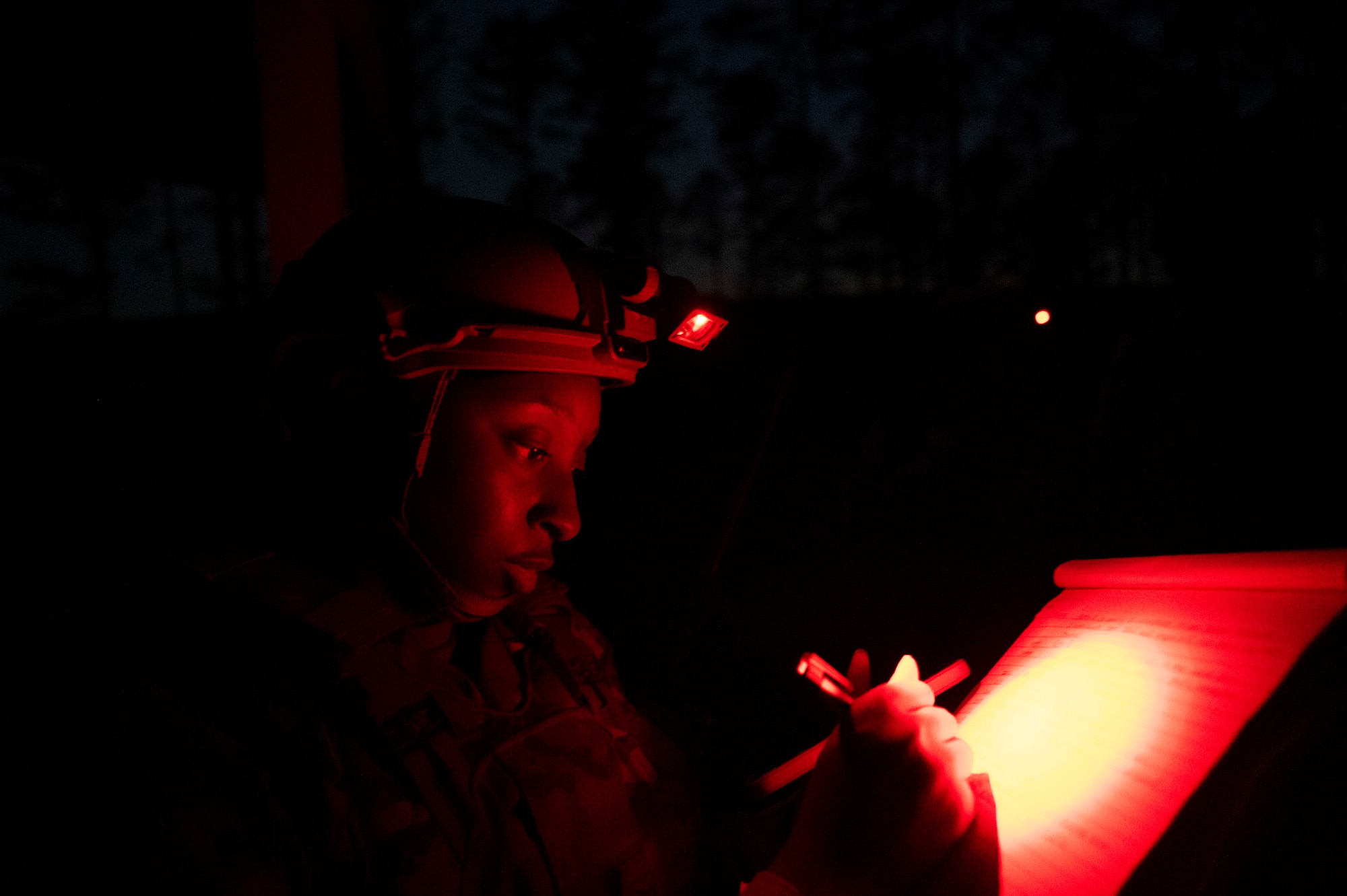 A woman writes on a piece of paper at night.