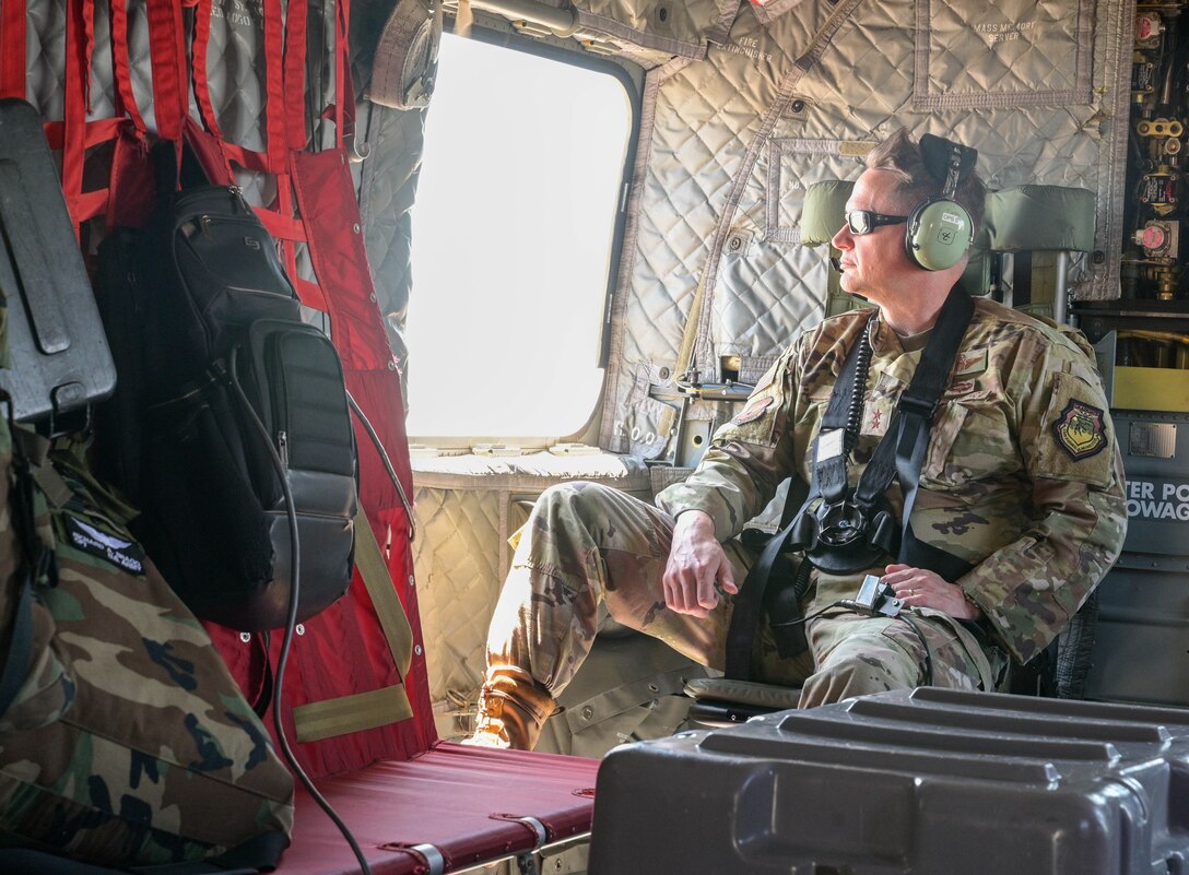 Airman looks out of a  window in a chinook.