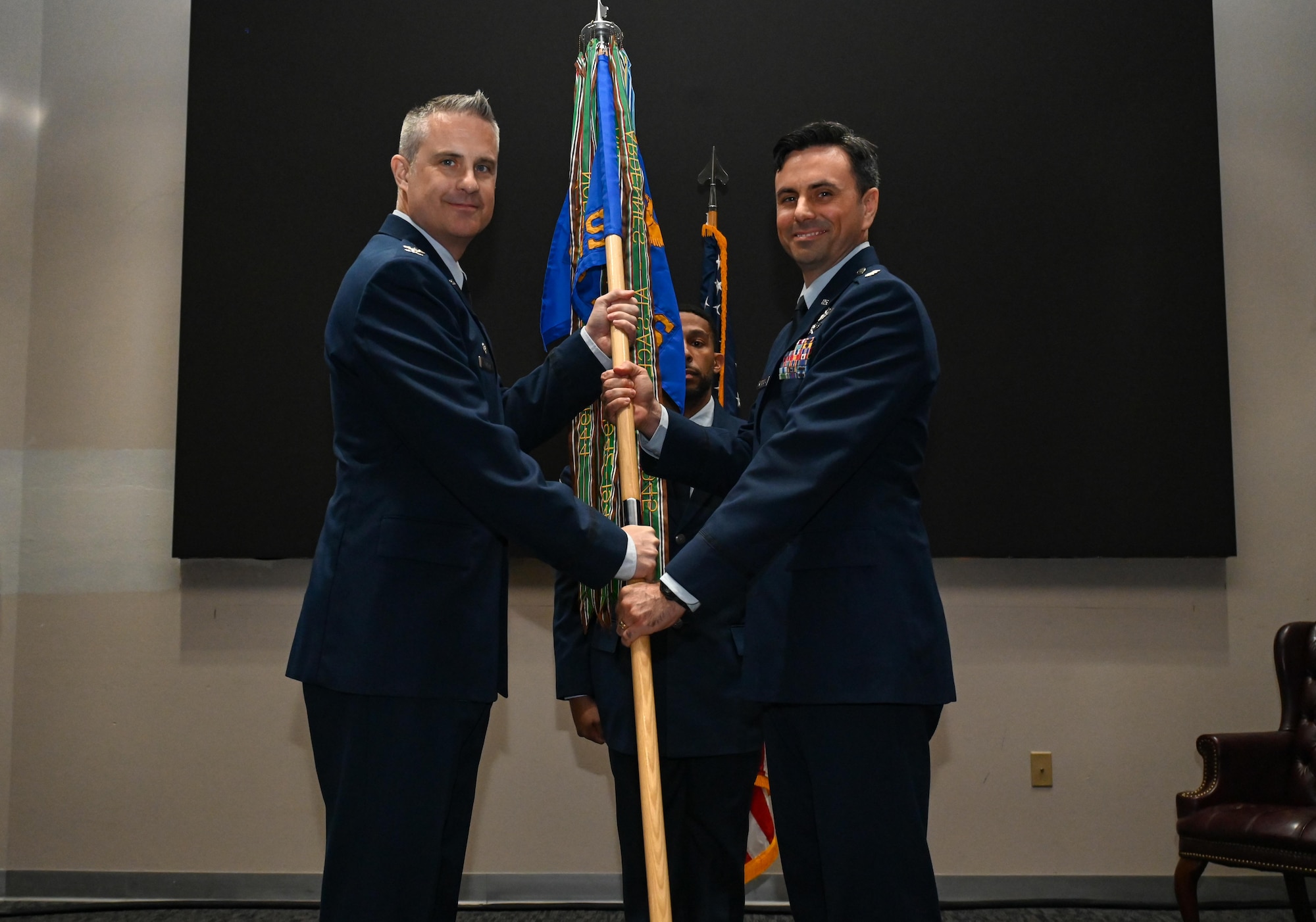 U.S. Air Force Col. Andrew Finkler, 850th Spectrum Warfare Group commander, left, passes the guidon to U.S. Air Force Lt. Col. Cameron Unterberger, 453rd Electronic Warfare Squadron commander, right, during the 453rd EWS change of command ceremony at Joint Base San Antonio-Lackland, Texas, June 3, 2024. The 453rd EWS is comprised of the Analysis Flight, Software Development Flight, Cyber Defense Operations Flight, Modeling, Simulation, and Analysis Engineering Flight, and Plans and Programs located at Joint Base San Antonio-Lackland. (U.S. Air Force photo by Capt. Benjamin Aronson)