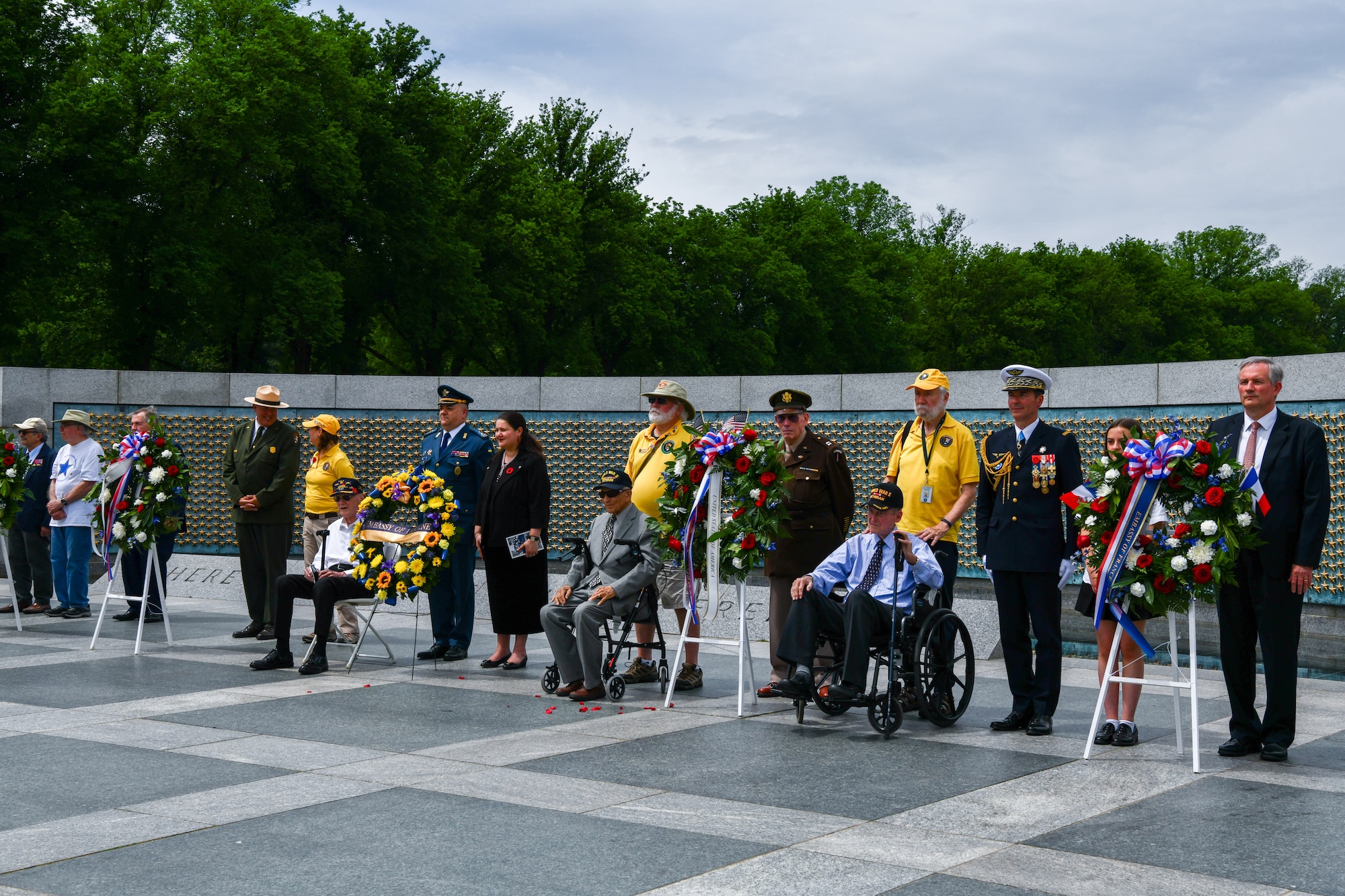 Ambassadors of France and Ukraine, World War II veterans, military members, and students stand at the World War II memorial.