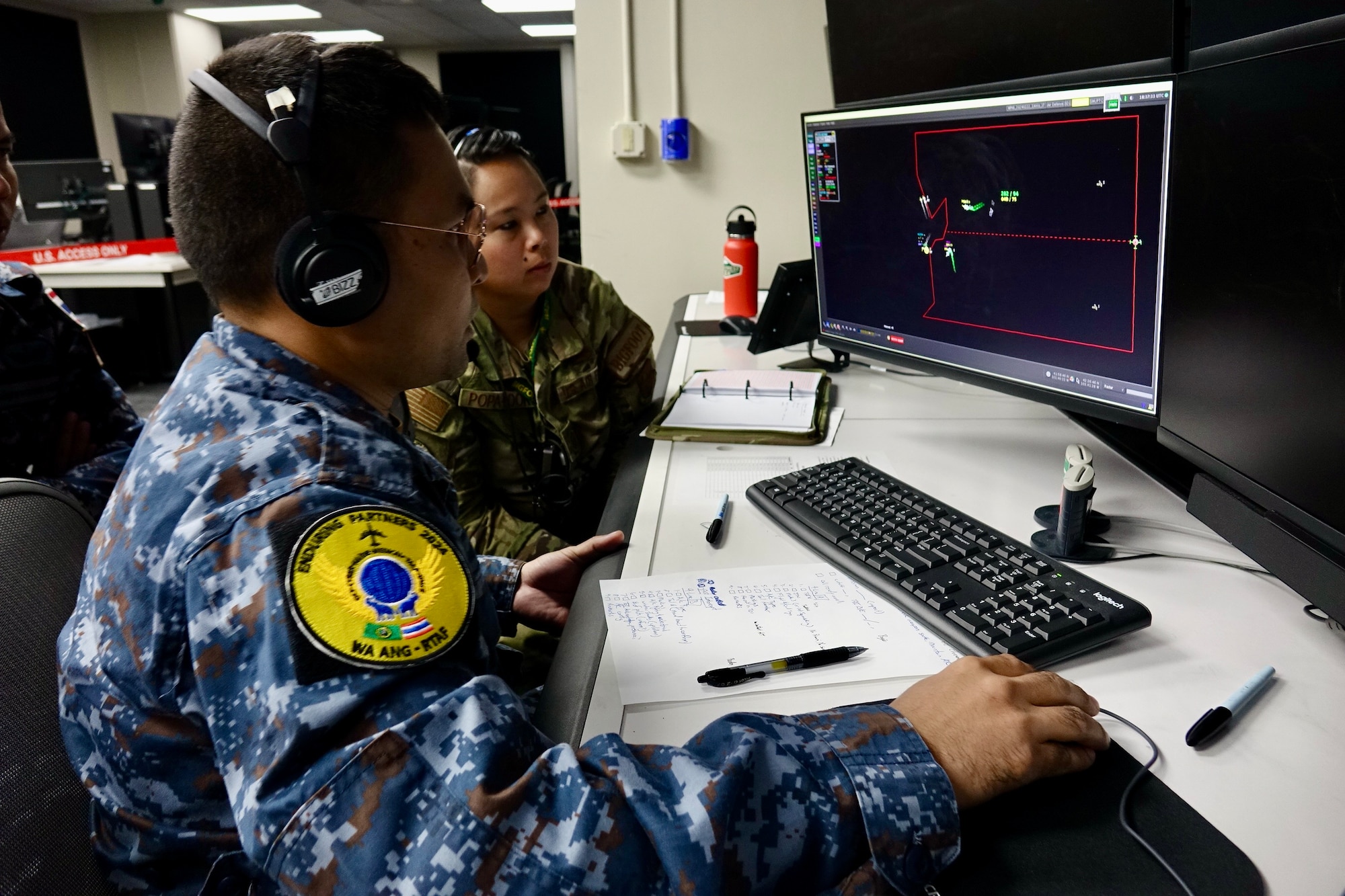 Airmen looking at computer screens.