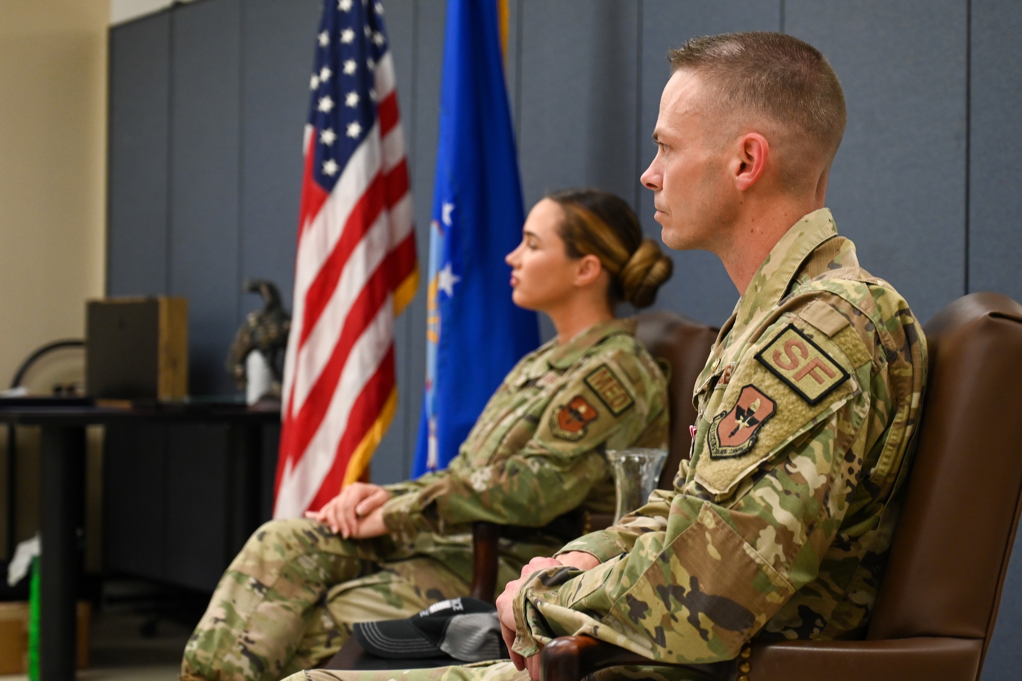 U.S. Air Force Master Sgt. Adam Neely, 97th Security Forces Squadron logistics readiness superintendent, and his daughter, 1st Lt. Samantha Collins, 81st Medical Group practice manager, listen to a speaker at Altus Air Force Base, Oklahoma, May 18, 2024. Neely was retired by his daughter, who was formerly an enlisted member herself (U.S. Air Force photo by Airman Lauren Torres)