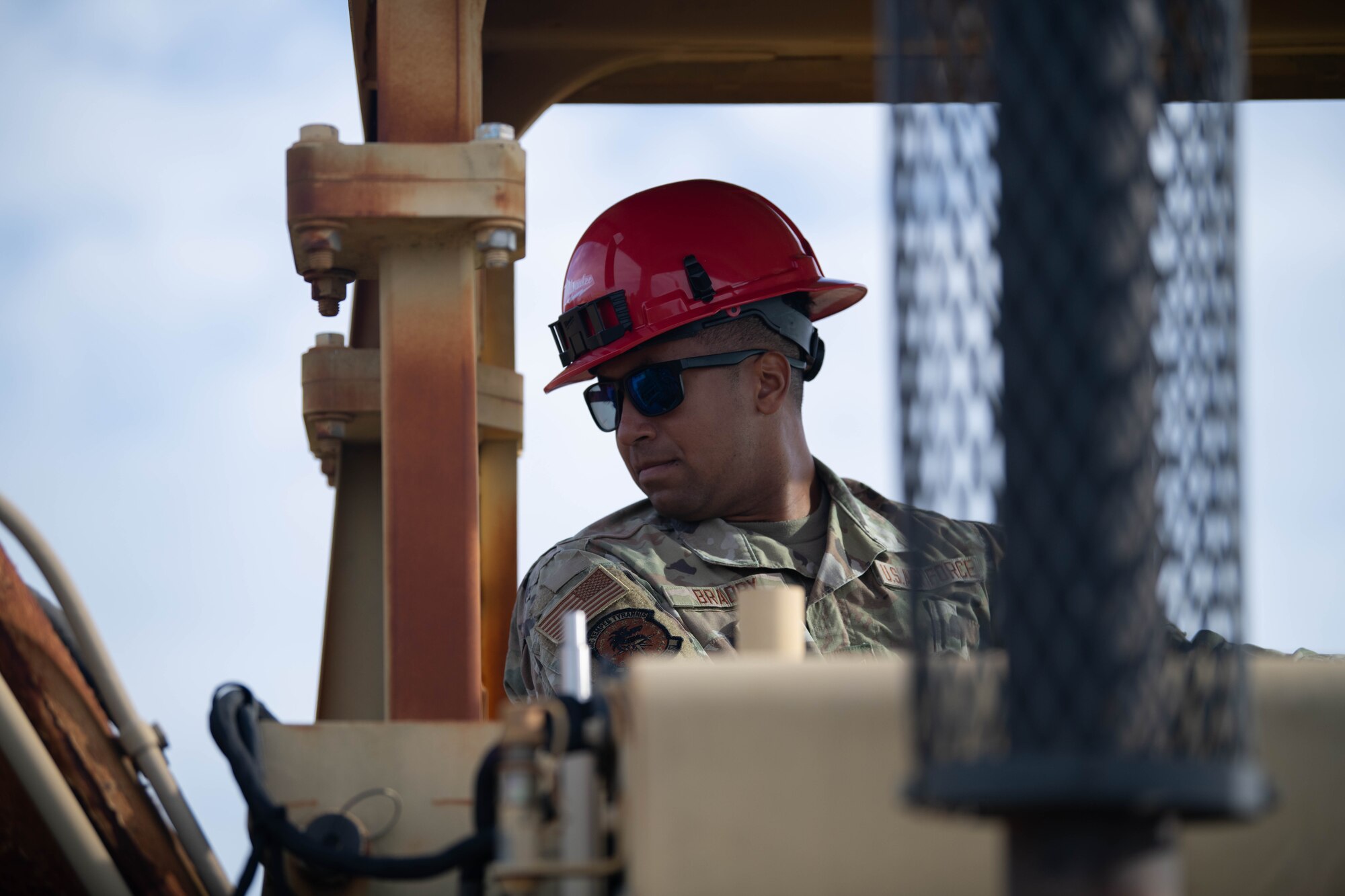 Airman operates a scraper, heavy equipment machine.