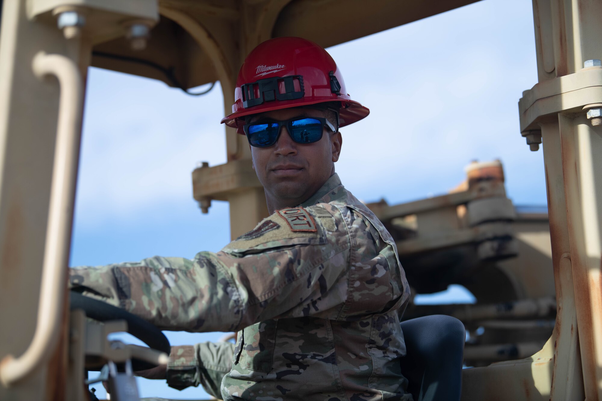 Airman operates a scraper, heavy equipment machine.