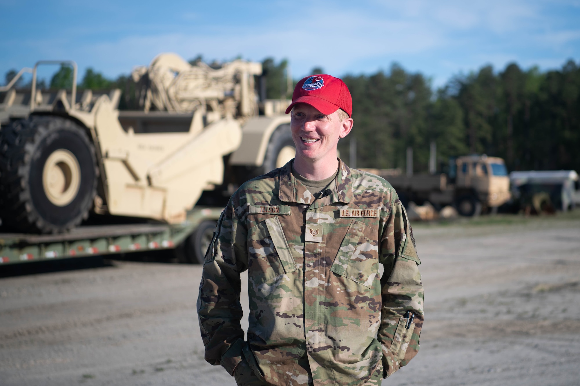 Airman stands in front of heavy equipment machines.