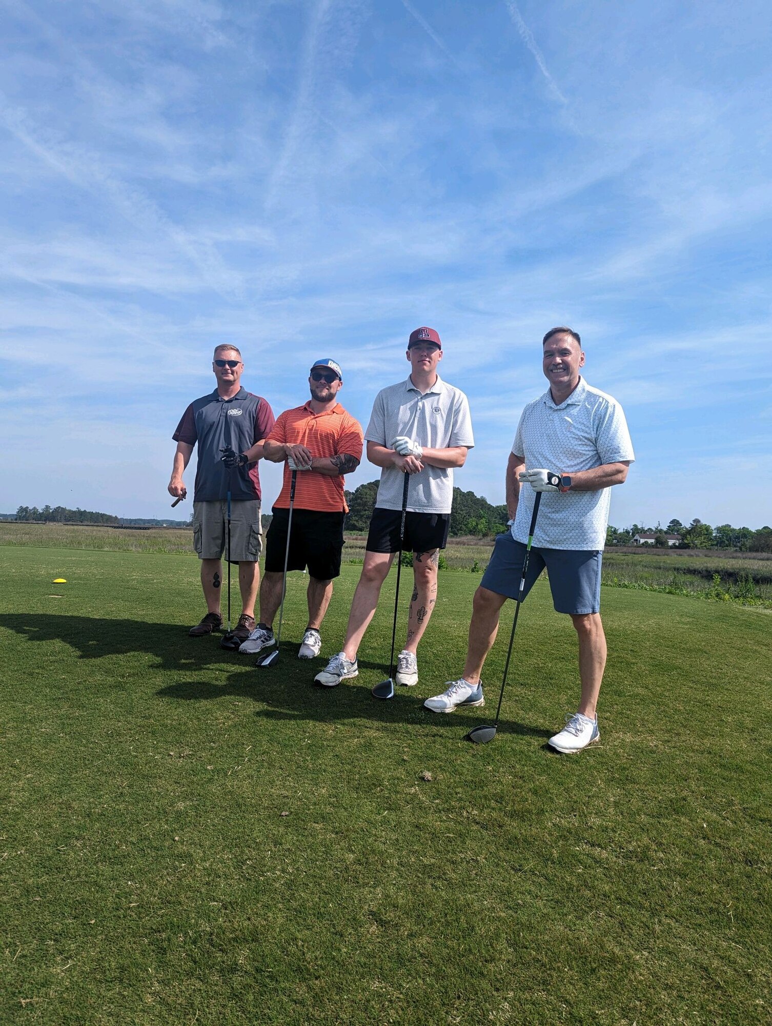 Four people pose for photo on golf course.
