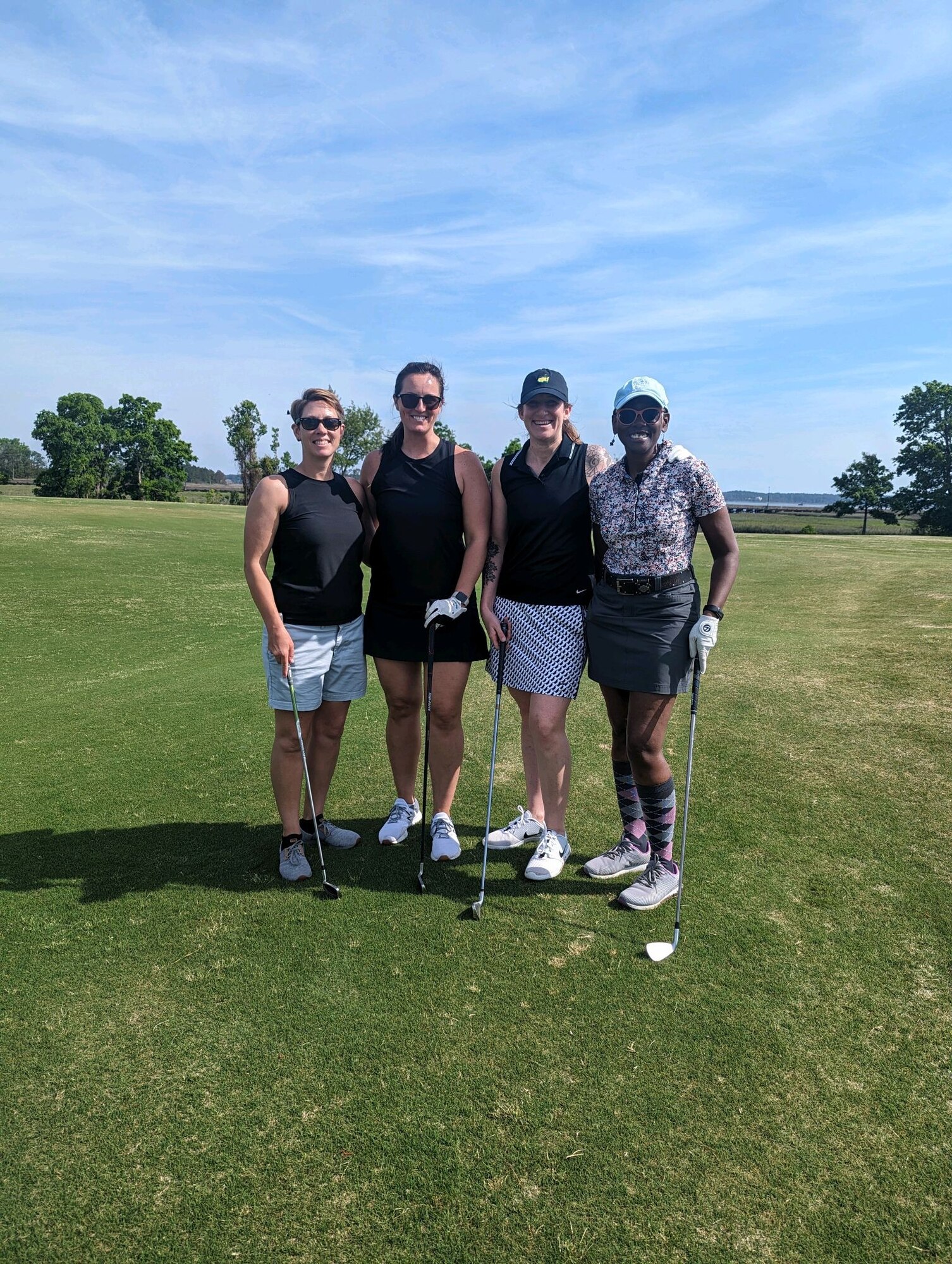 Four people pose for photo on golf course.