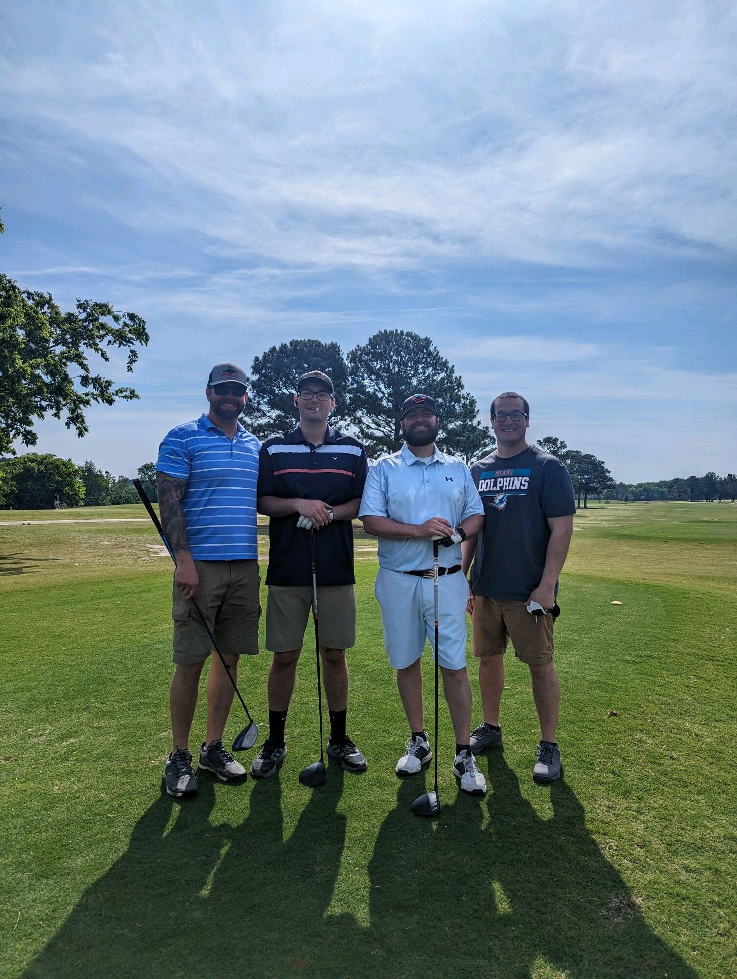 Four people pose for photo on golf course.