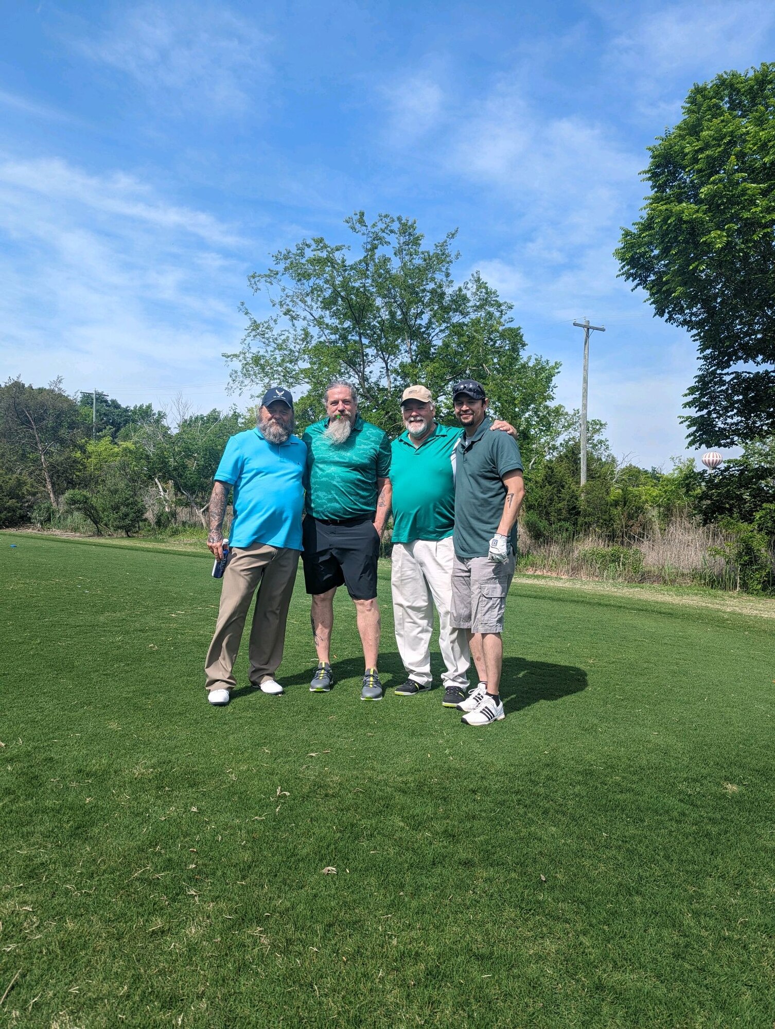 Four people pose for a photo on golf course.