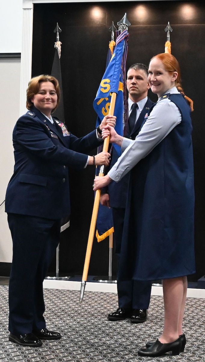 U.S. Air Force Col. Angelina Maguinness, 17th Training Wing commander, passes the guidon to Maj. Kelly Griffith, incoming 17th Comptroller Squadron commander, during the change of command ceremony at the Powell Event Center, Goodfellow Air Force Base, Texas, June 4, 2024. Griffith was formerly the USAFE-AFAFRICA FM Deputy Branch Chief leading a team performing budget integration, execution and funds control for a $1.7B program. (U.S. Air Force photo by Staff Sgt. Nathan Call)