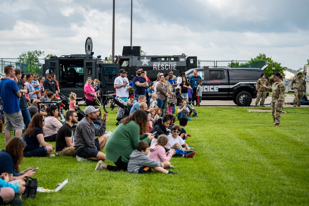 Tech. Sgt. Pina stands in front of a crowd of people siting and standing in the grass