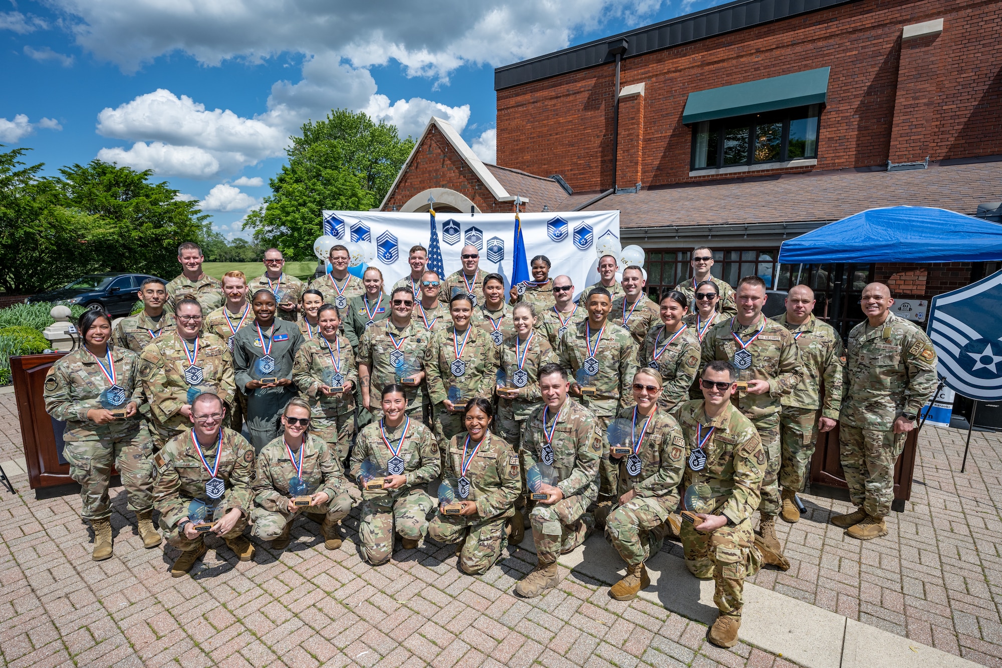 A large group photo of military members outdoors celebrating making promotion