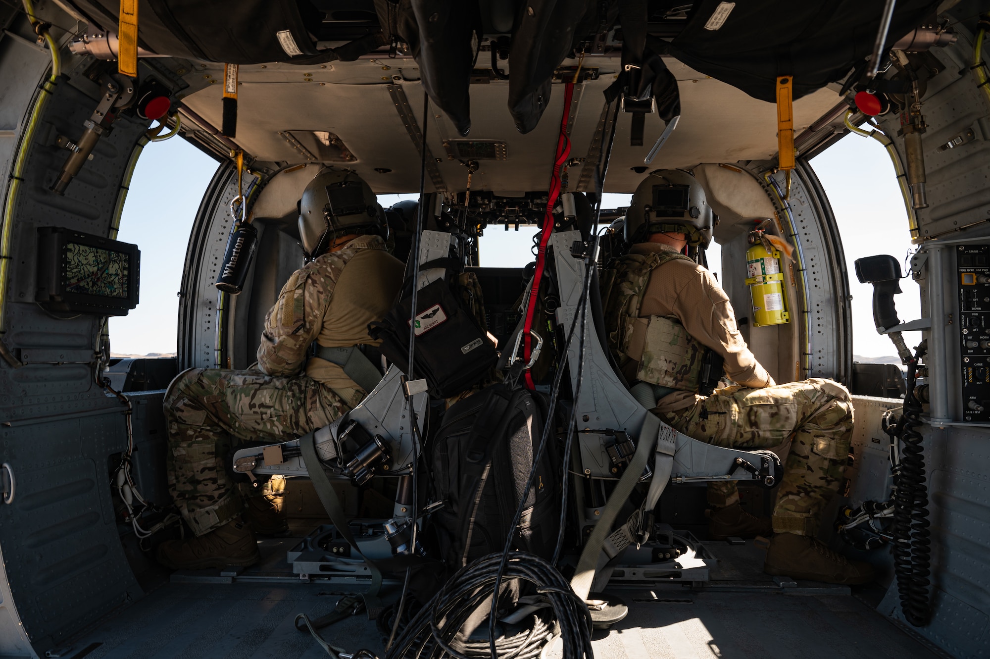 Two Airmen sitting in the back of a helicopter