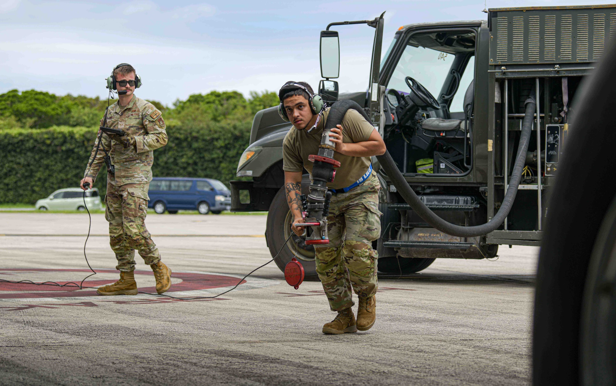 U.S. Air Force Senior Airman Michael Keller, left, 909th Aircraft Maintenance Unit flying crew chief, and Airman 1st Class Carlos Alberto Rivera II,  18th Logistics Readiness Squadron petroleum, oils and lubricants apprentice, perform hot-pit refueling on a KC-135 Stratotanker.