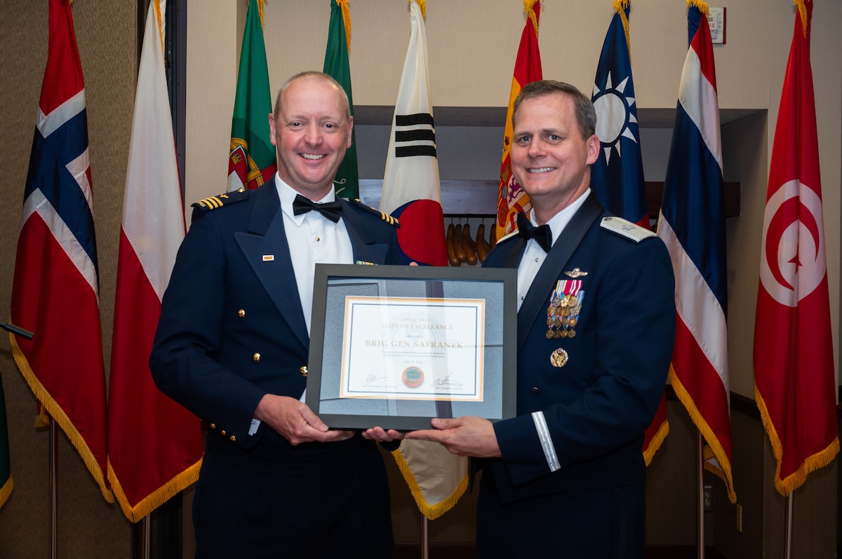 Two men hold award during the AFSAC/FLO International reception