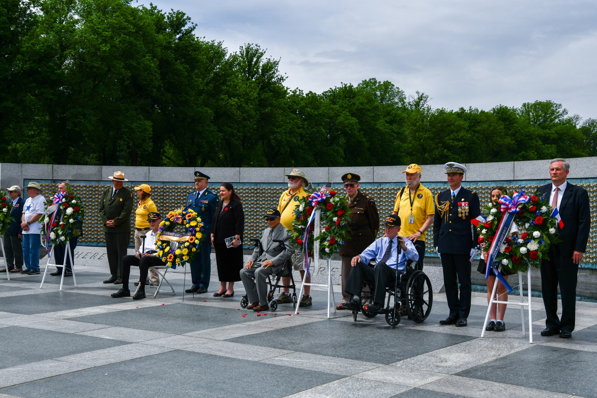 Ambassadors of France and Ukraine, World War II veterans, military members, and students stand at the World War II memorial.