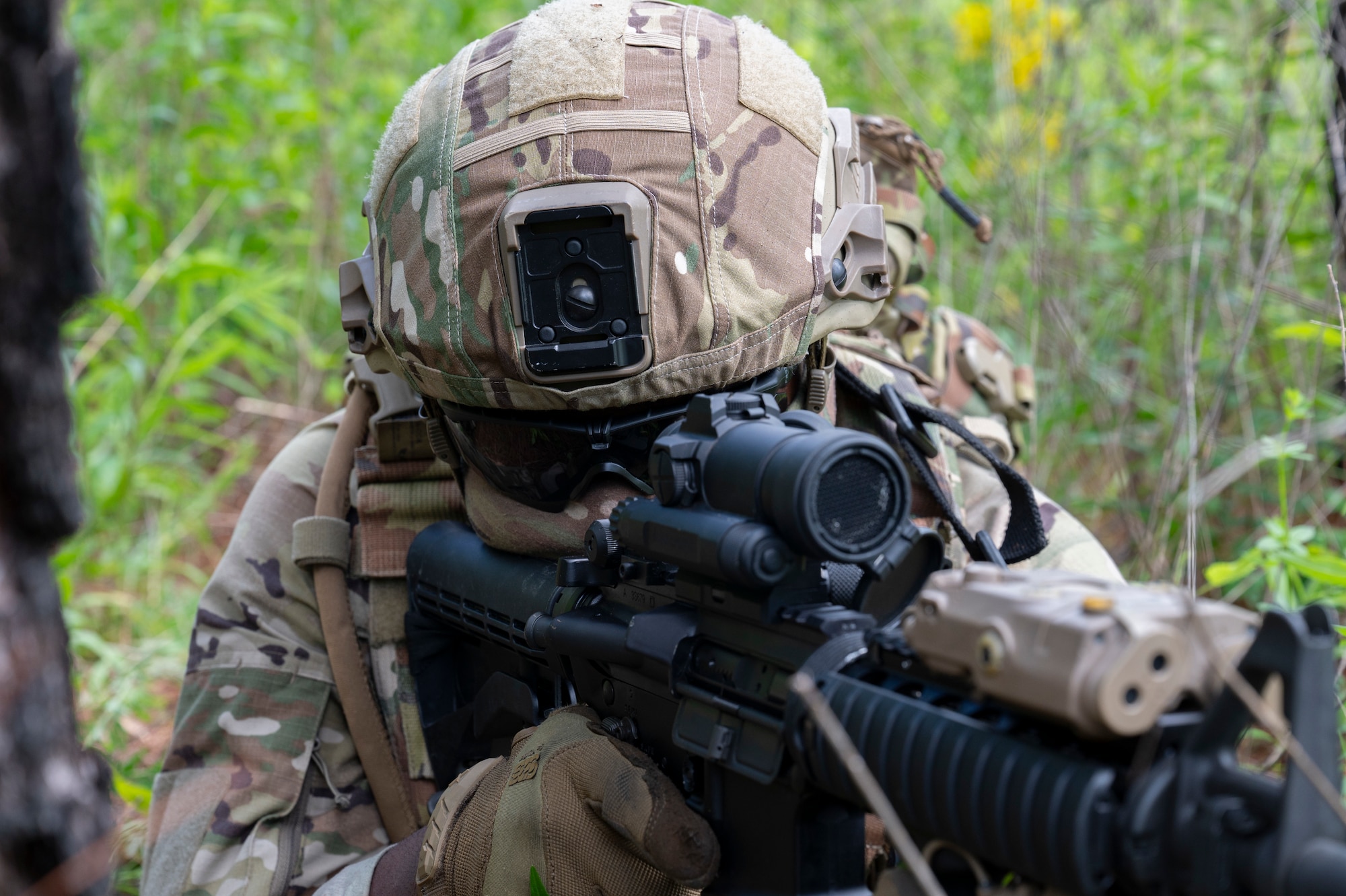 An Airman lays down aiming his rifle, looking through the scope.