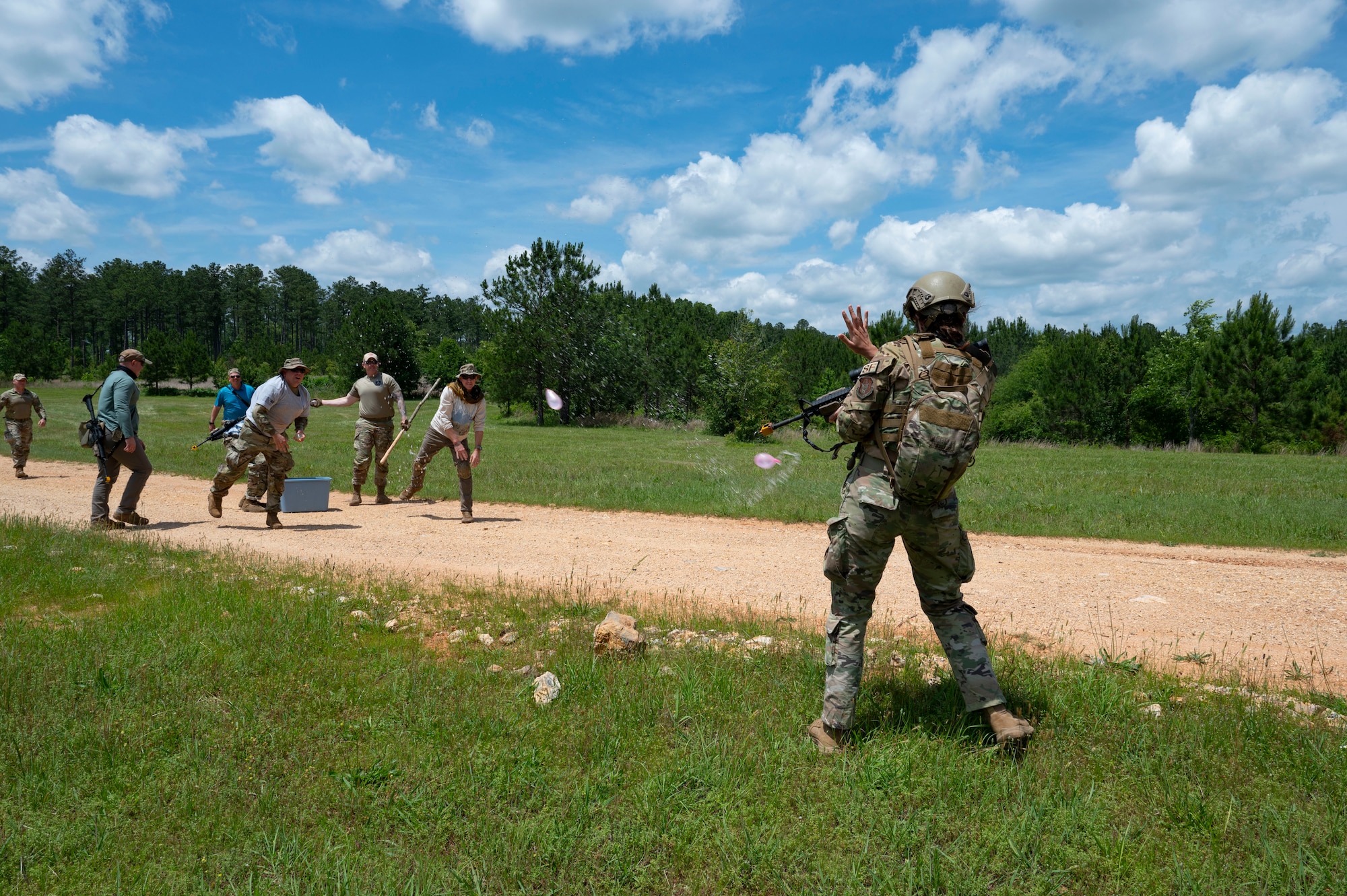 People on the left throw water balloons at an Airman on the right.