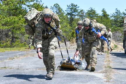 103rd Rescue Squadron pararescuemen, assigned to the New York Air National Guard 106th Rescue Wing, pull a patient toward the evacuation location during an exercise at F.S. Gabreski Air National Guard Base, N.Y., May 4, 2024. During the exercise, 106th Security Forces Squadron secured the area for the 103rd Rescue Squadron pararescuemen to parachute in, recover the injured personnel and provide medical care and transport via an HH-130J Combat King II aircraft flown by the 102nd Rescue Squadron.