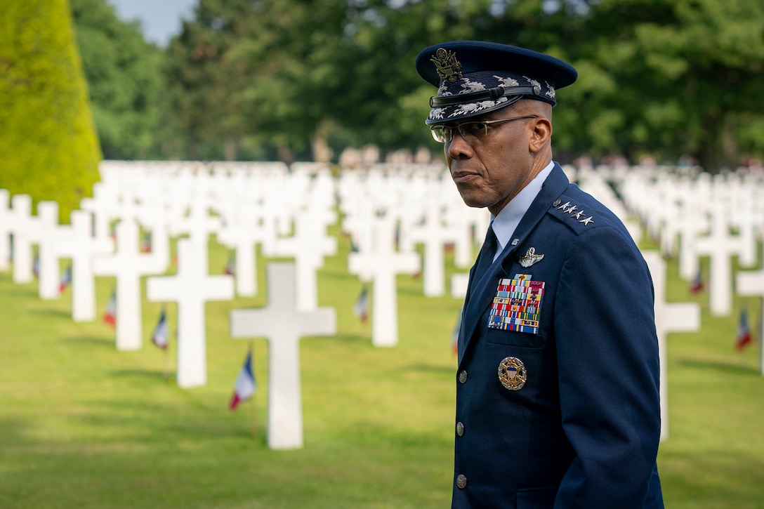Air Force Gen. CQ Brown, Jr., walks by rows of white crosses marking gravesites at a cemetery.
