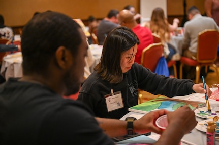 U.S. Air Force Airman 1st Class Geneva Nguyen, Public Affairs Specialist at the 11th Wing, Joint Base Anacostia-Bolling, paints her interpretation of the four pillars of her life during the JBAB wellness retreat weekend in Herndon, Virginia on May 3, 2024. The participants used paint therapy as an outlet for emotional expression and stress-reduction, encouraging a cathartic release of emotions. (U.S. Air Force photo by Airman Shanel Toussaint)