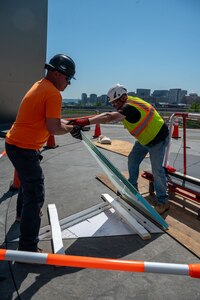 two contractors carefully place heavy non-slip glass coverings over a sheet of light emitting diodes in a triangular-shaped star point at the base of the U.S. Air Force Memorial