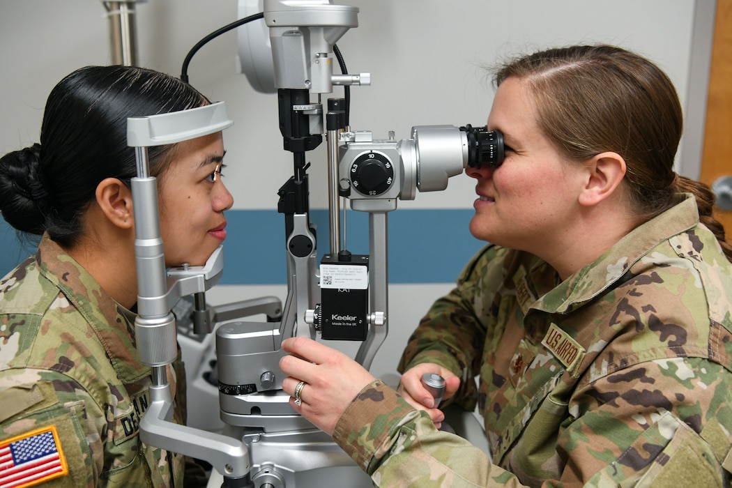 Army Staff Sgt. Mary De Guzman receives an eye exam from Air Force Maj. Adrian Hulbert, optometrist
