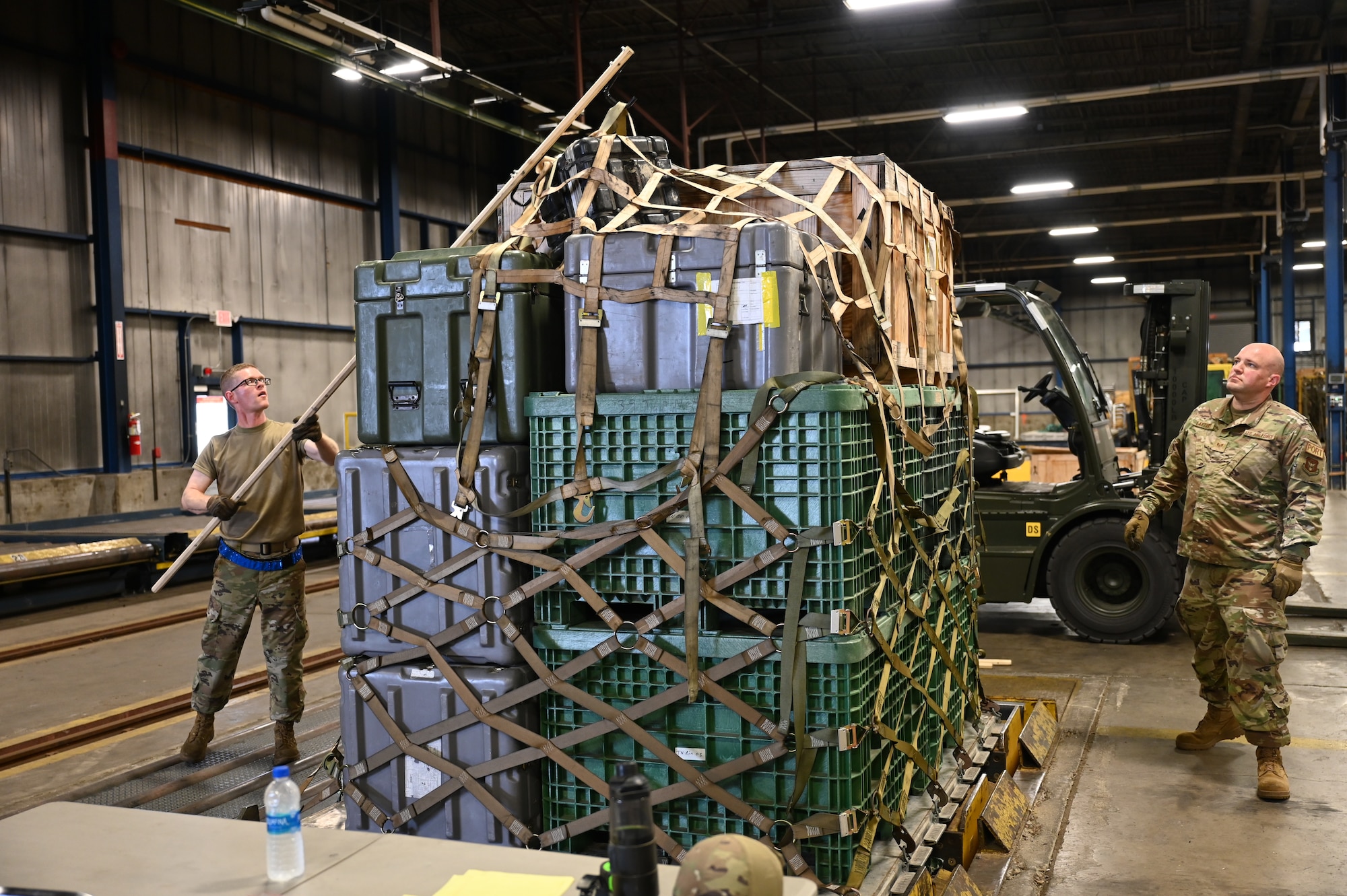 Staff Sgt. Daniel Schnaars, 87th Aerial Port Squadron air freight representative, uses a pallet spear to grab and lift a top net from a tall pallet so Staff Sgt. Kirk Laytart, 87th APS passenger service representative, can pull it off and away from the pallet during the breaking down process at Wright-Patterson Air Force Base, Ohio, May 4, 2024. The Airmen are developing the spear to replace the inefficient ladder system currently in use to remove nets from pallets and would also be a more safe option.