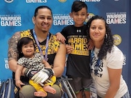 Retired Army Sgt. Joel Rodriguez, his wife Liannie - his caregiver – pose with their children after Team Army medaled silver in the wheelchair basketball game at the 2022 Warrior Games in Orlando, FL