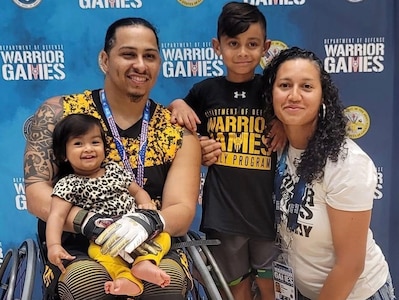 Retired Army Sgt. Joel Rodriguez, his wife Liannie - his caregiver – pose with their children after Team Army medaled silver in the wheelchair basketball game at the 2022 Warrior Games in Orlando, FL