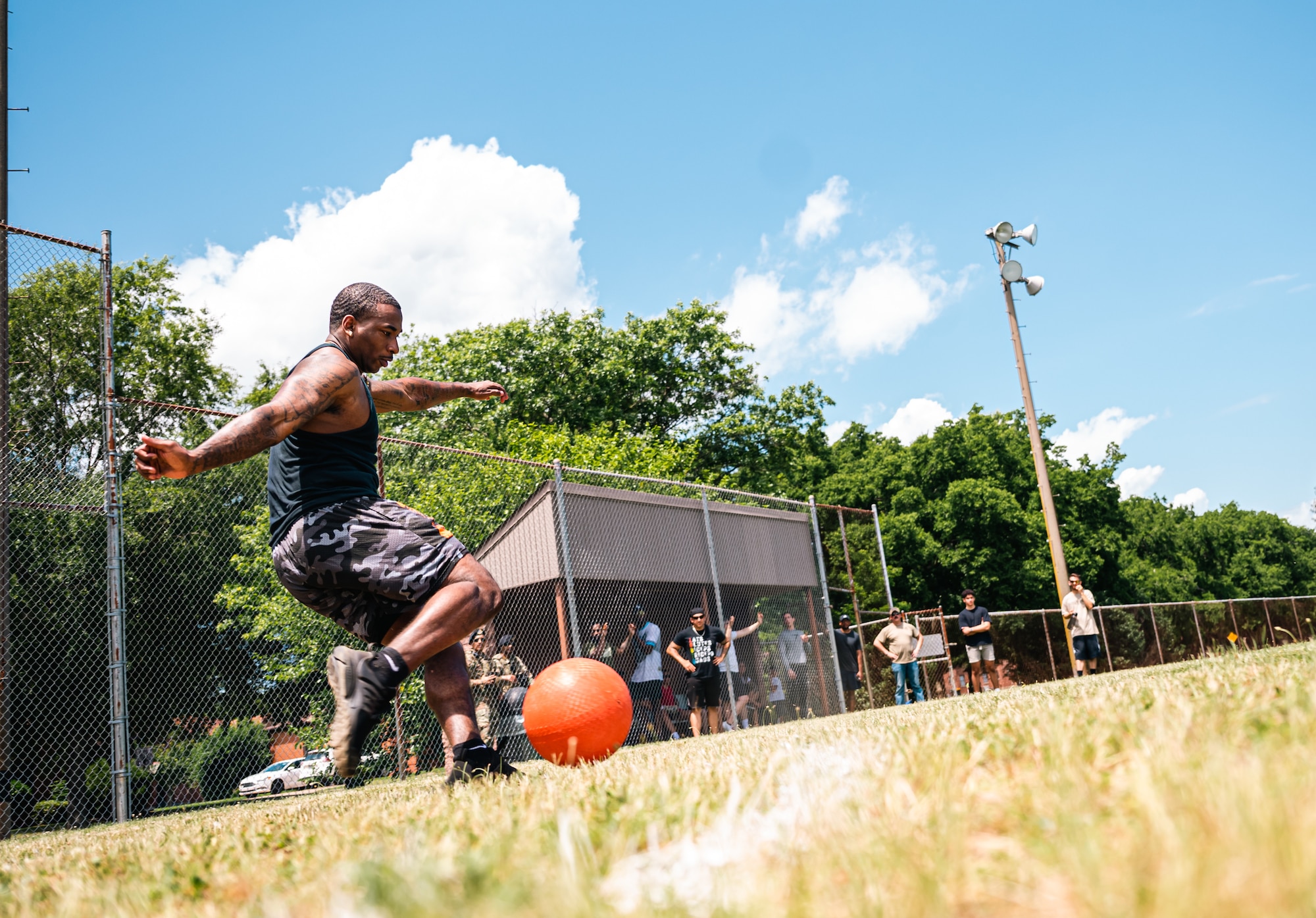Airmen in black clothes prepares to kick kickball