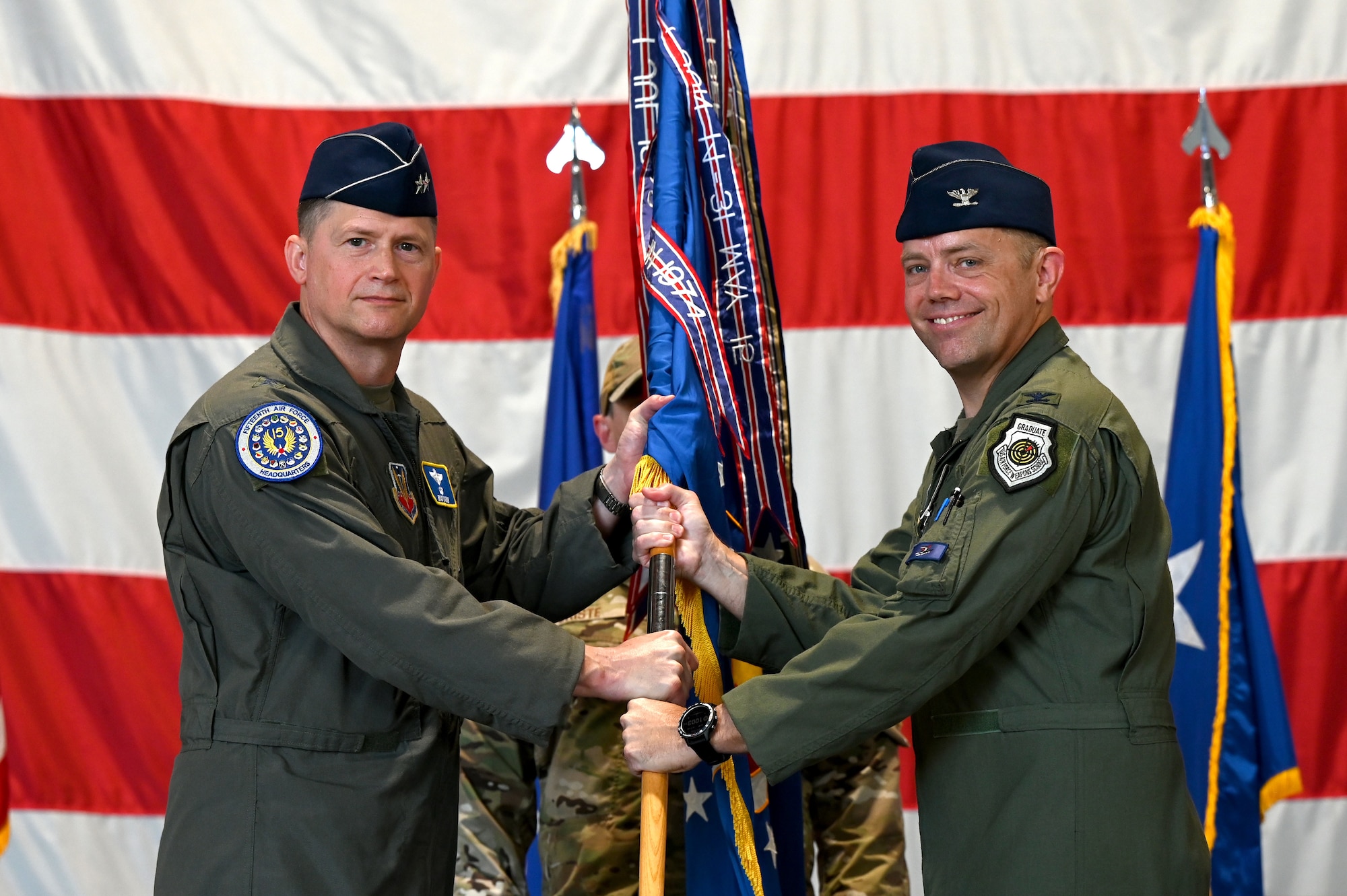 U.S. Air Force Maj. Gen. David Lyons, Fifteenth Air Force commander, left, receives the 20th Fighter Wing guidon from Col. Kristoffer Smith, outgoing 20th FW commander, during a change of command ceremony at Shaw Air Force Base, S.C., June 7, 2024. The passing of the guidon symbolizes the transfer of command from Smith as the commanding officer of the 20th FW after two years of leading the wing. (U.S. Air Force photo by Staff Sgt. Kelsey Owen)