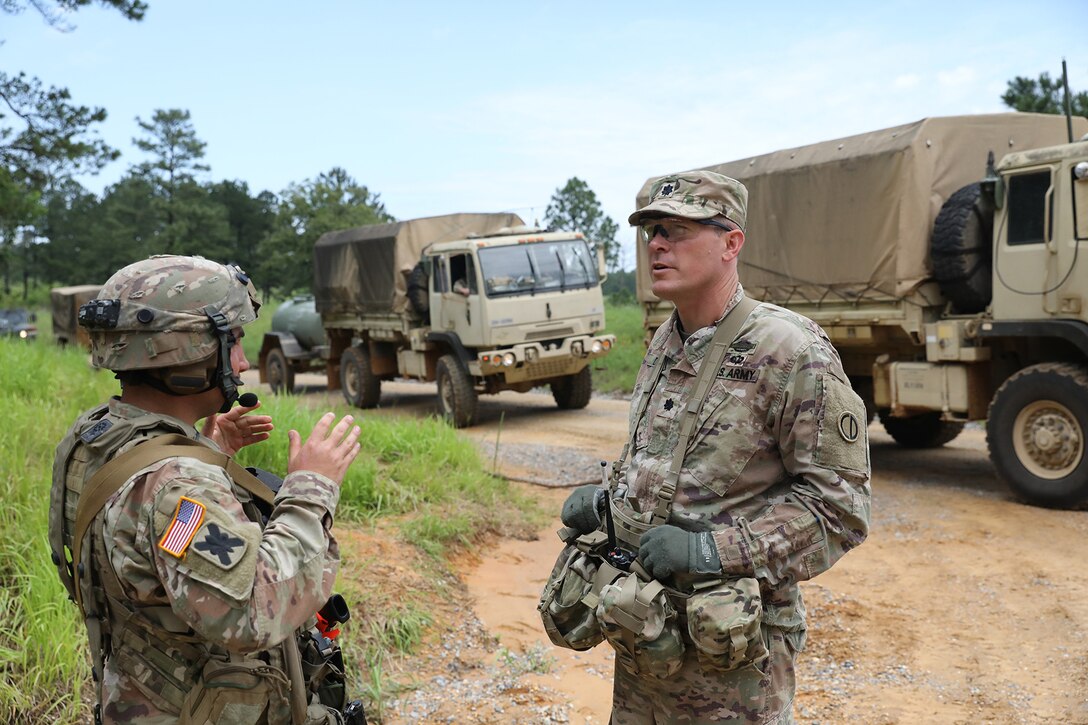 Lt. Col. Cassidy Dauby, Battalion Commander, 2-346th Training Support Battalion, Camp Shelby, Mississippi, talks with Capt. John Lombardo, Bravo Company, 2-156th Infantry Battalion, Louisiana National Guard, New Iberia, Louisiana, as trucks transport Soldiers to a location during XCTC 24-01.