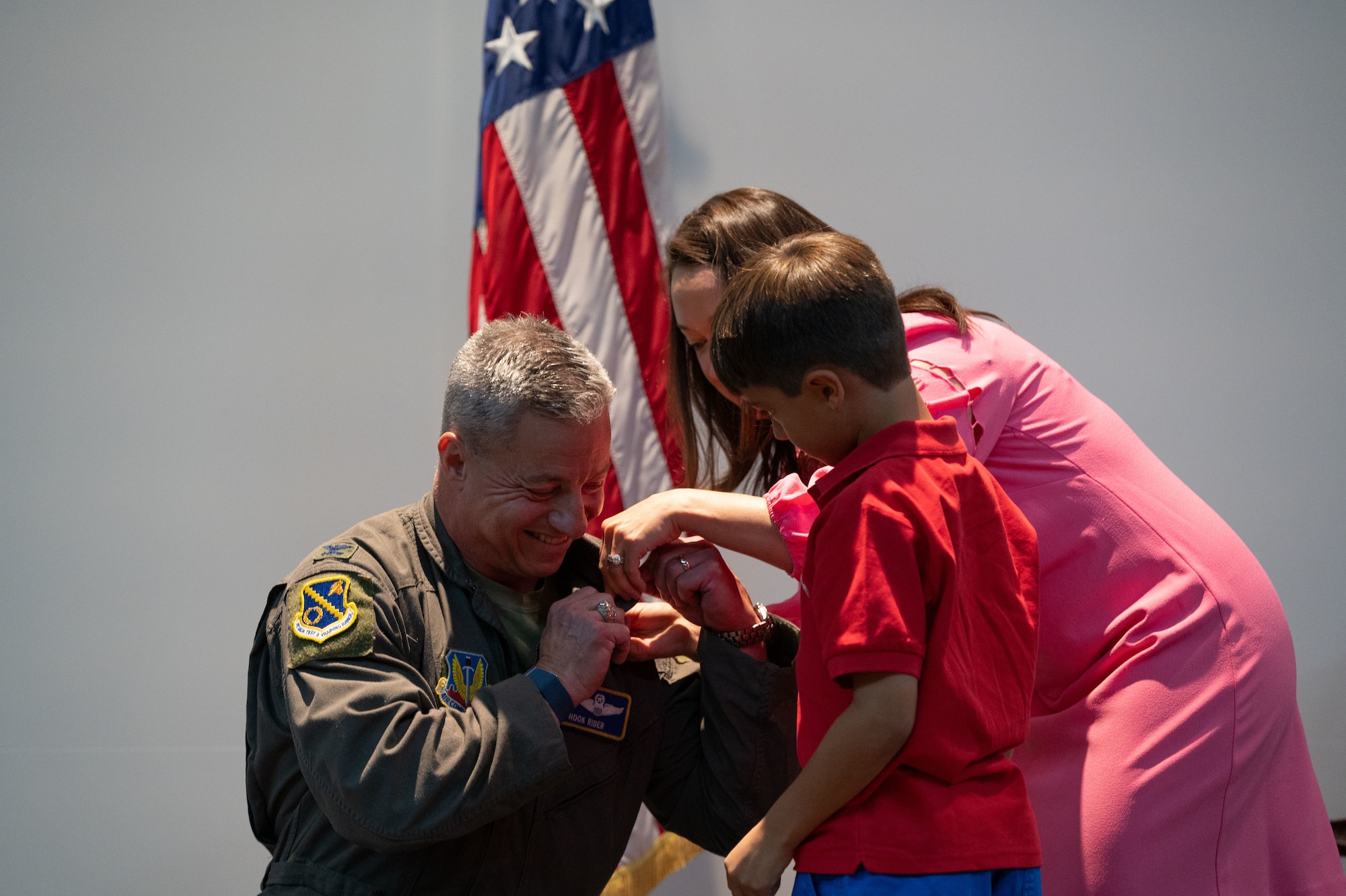 A woman helps her son attach a retirement pin to his father's uniform.
