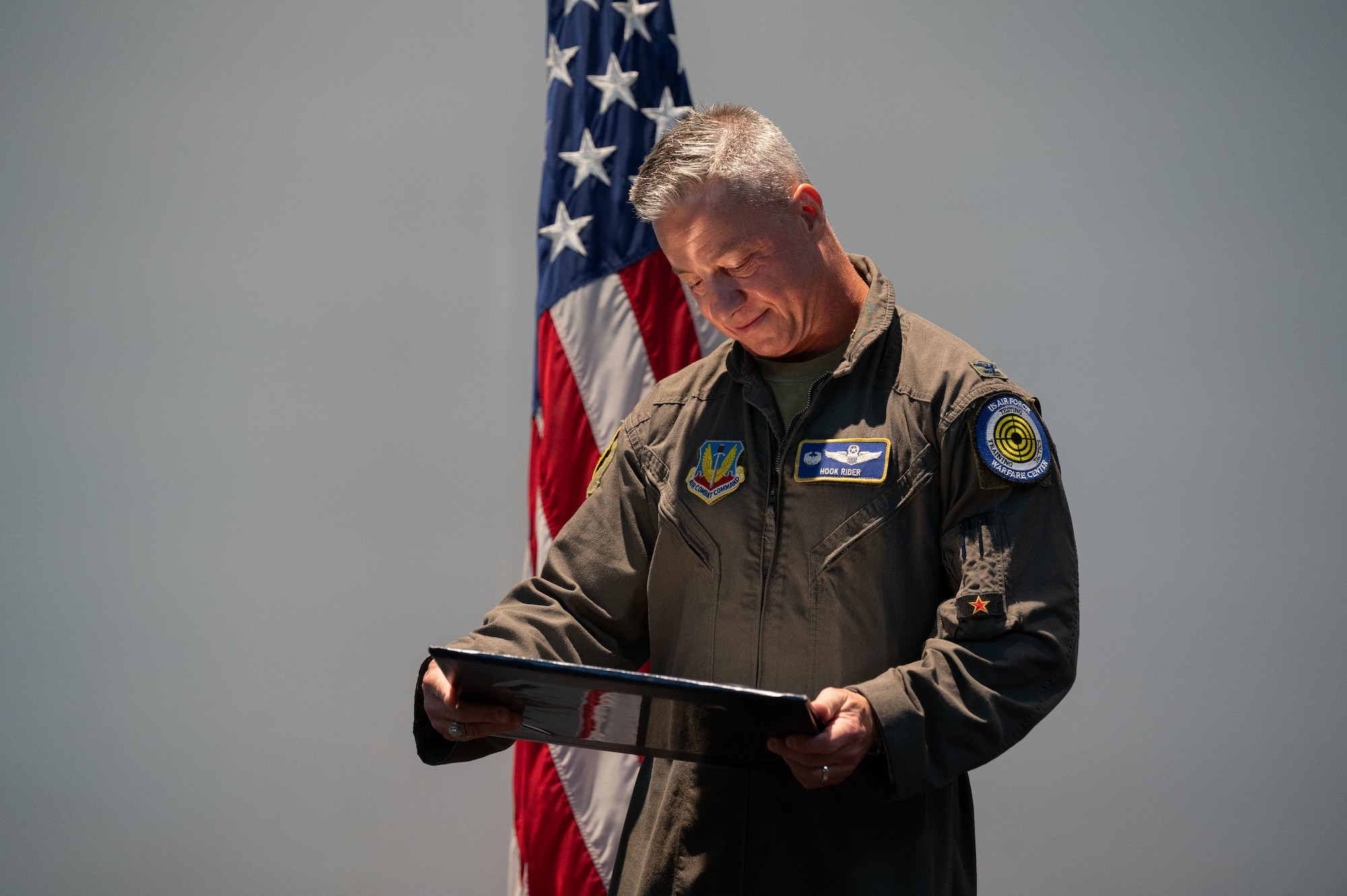 A man in uniform looks at a certificate on stage.
