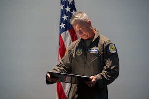 A man in uniform looks at a certificate on stage.
