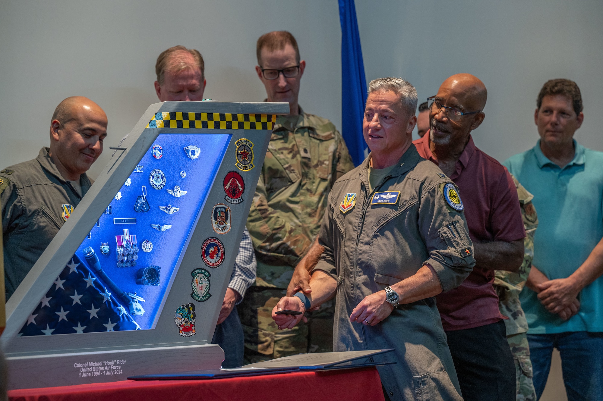 A group of people gather around a shadow box.
