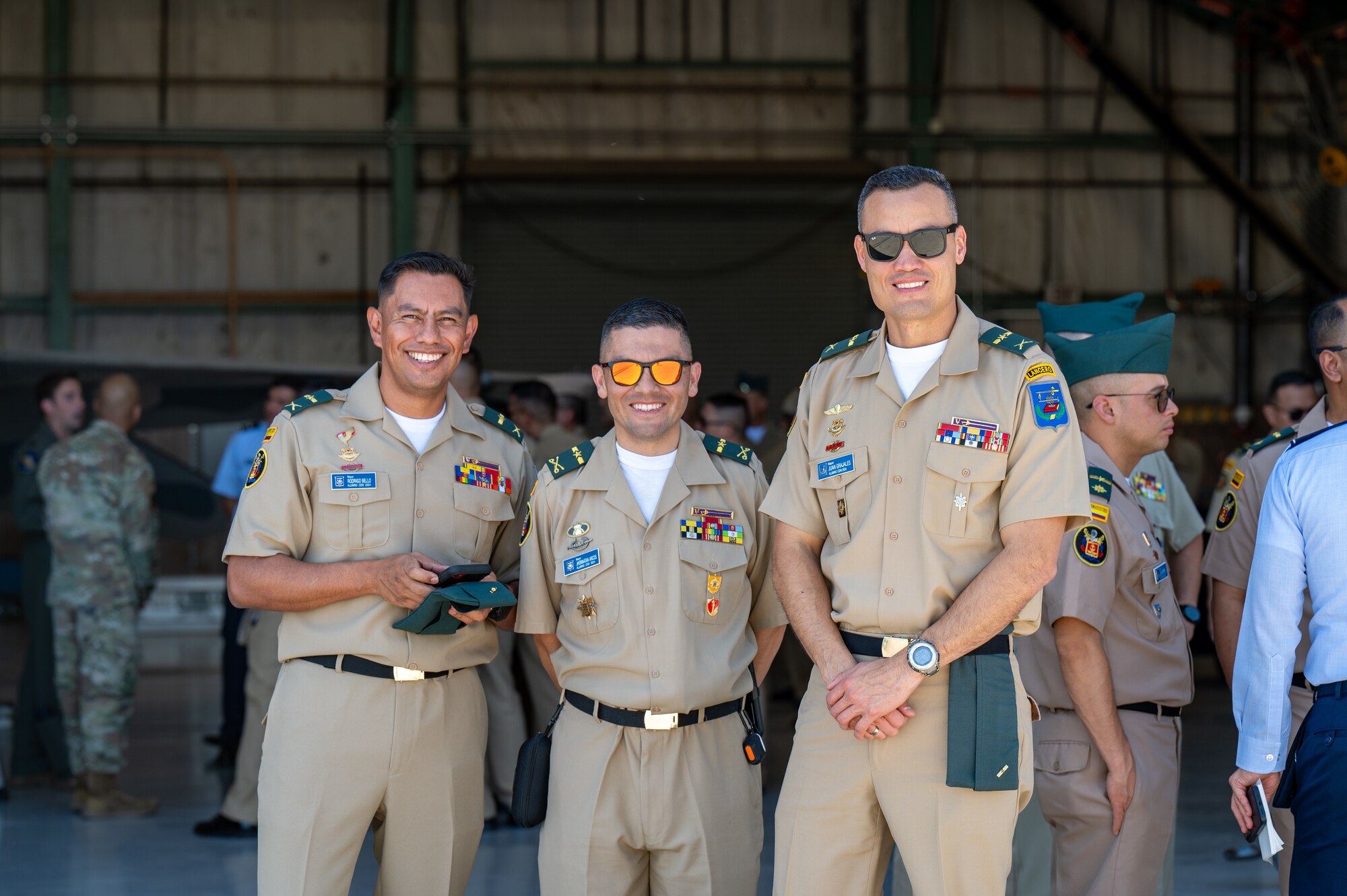 Three men stand and smile for a photo.
