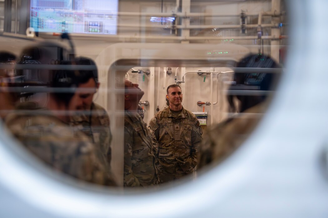 a photo of military members in a hyperbaric chamber through the port hole
