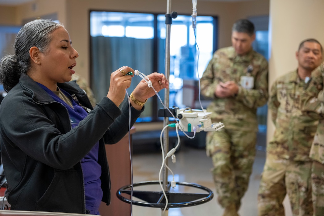 A military nurse shows other members a new IV machine