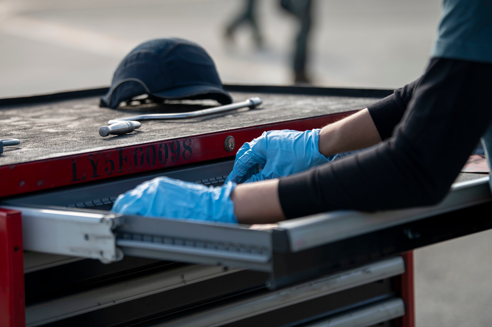 A maintainer from the Republic of Singapore grabs a tool in a toolbox.