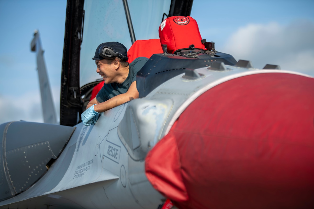 A maintainer from the Republic of Singapore Air Force sits in the cockpit of an F-16 aircraft.
