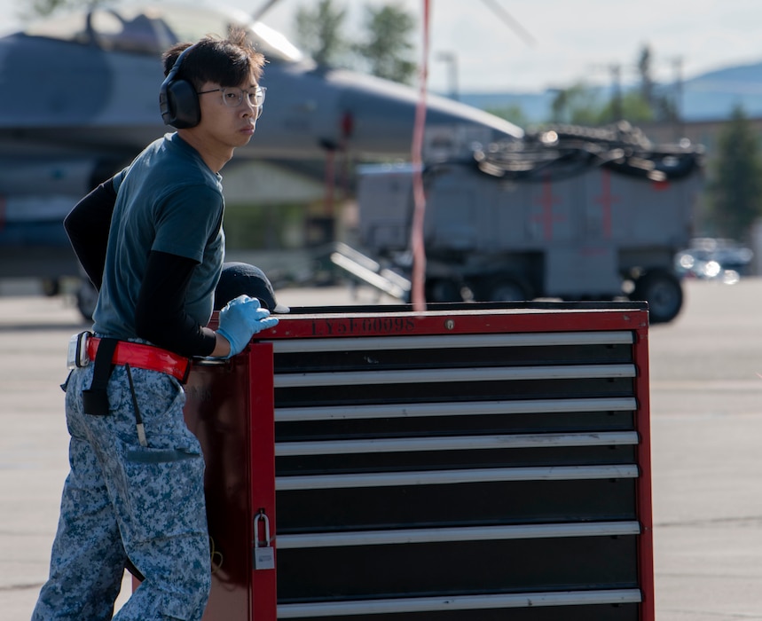 A maintainer from the Republic of Singapore 425th Fighter Squadron pushes a toolbox across the flightline.