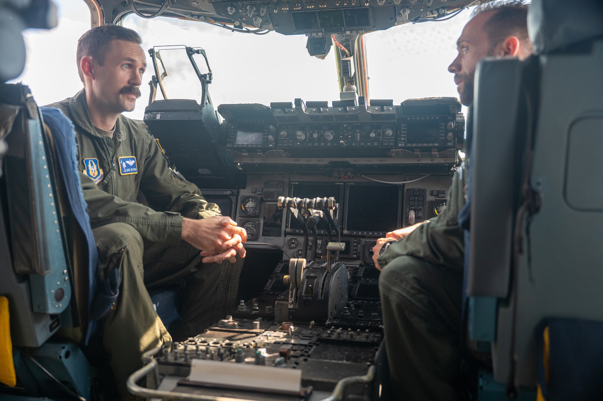 In the cockpit of a C-17 Globemaster III cargo aircraft, Maj. Christopher Wojtowicz, at left, a C-17 pilot with the U.S. Air Force Reserve 300th Airlift Squadron Joint Base Charleston, S.C., discusses his role in strategic airlift with Gerald "Titan" Gross, a German Air Force Eurofighter Typhoon pilot during the ILA Berlin 2024 Air Show held in Berlin, Germany, June 8, 2024. The highly-attended international aviation event allowed aircrews from multiple countries to discuss their interoperability and share best practices. (U.S. Air Force photo by Tech. Sgt. Della Creech)