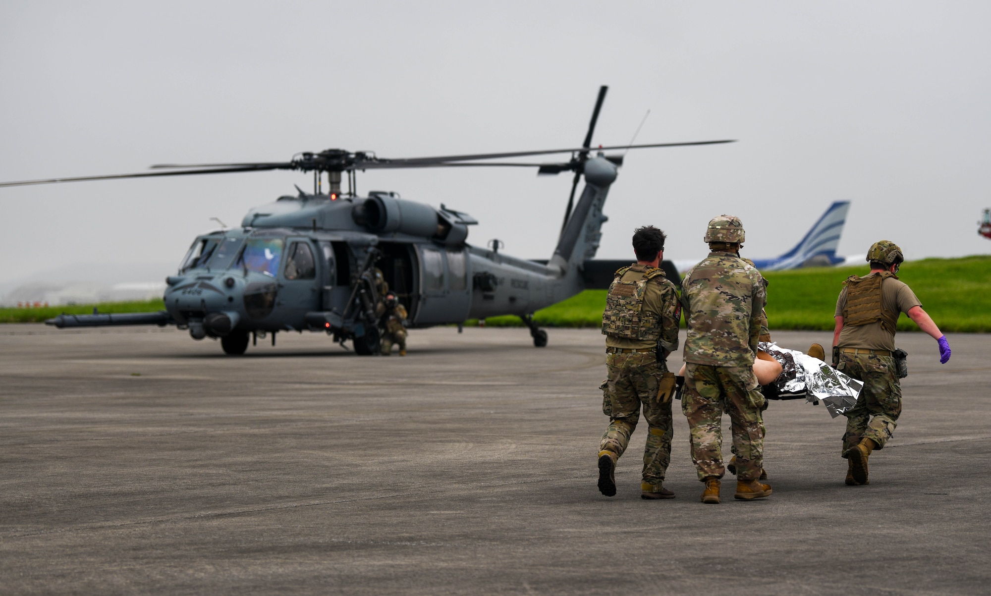 U.S. Air Force Airmen and a U.S. Army Soldier carry a simulated patient to an HH-60G Jolly Green II