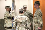 Four people in military uniforms stand in a formation