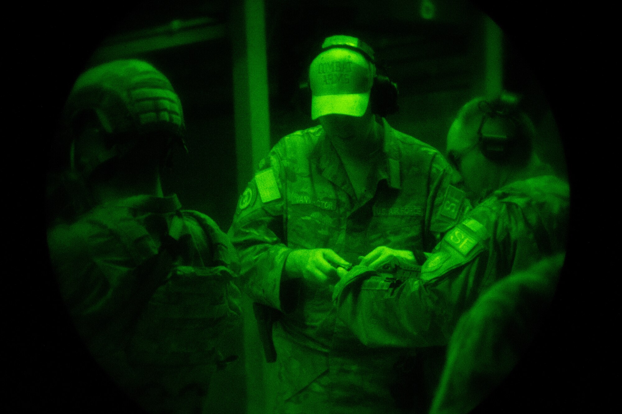 A uniformed instructor wearing a hat that reads "COMBAT ARMS" assists a student, also uniformed. Both appear to be members of the U.S. Air Force.