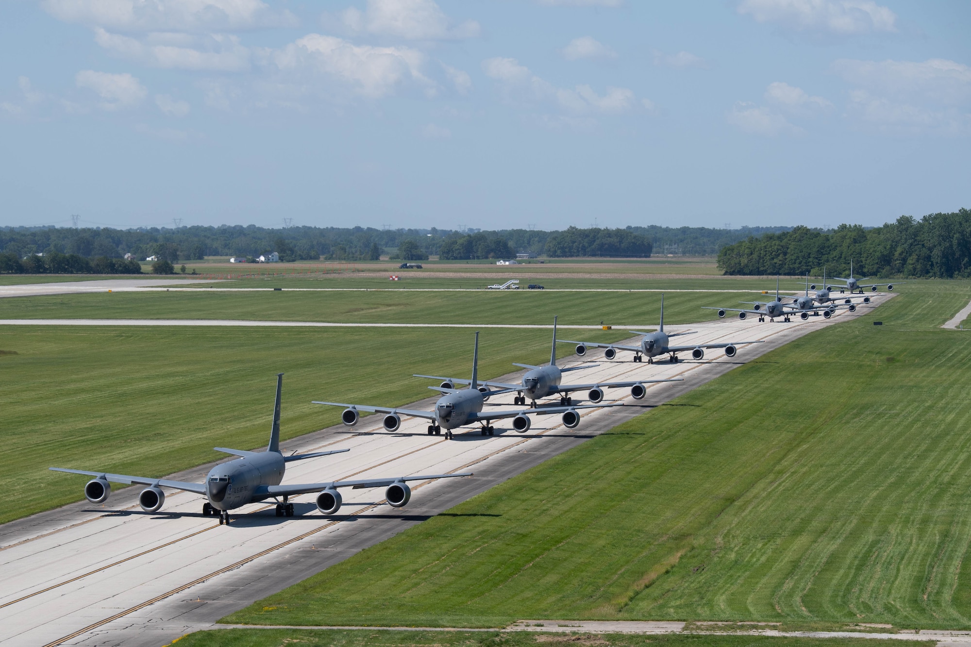 Multiple KC-135R Stratotankers taxi on a runway. The photograph appears to be taken from a height significantly above the aircraft and runway.